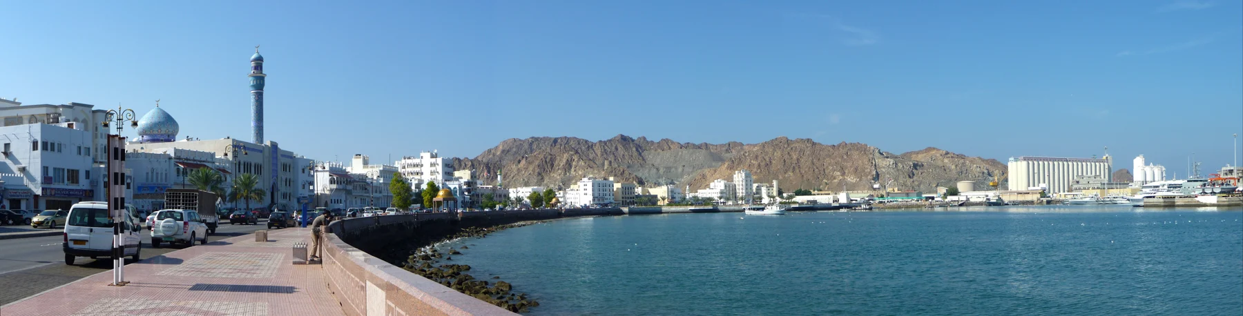 Blue water, white waterfront buildings and rugged mountains at Mutrah in Muscat